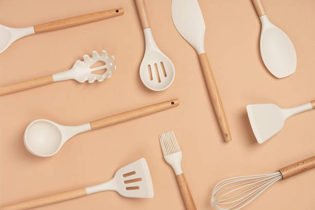 motif fabriqué à partir d’un ensemble d’ustensiles de cuisine. outils de cuisine en silicone avec poignée en bois sur fond beige. vue du haut pose plate - magasin dustensiles de cuisine photos et images de collection