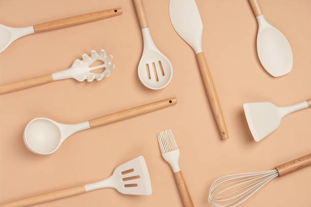pattern made from cooking utensil set. silicone kitchen tools with wooden handle on beige background. top view flat lay - utensílio de cozinha imagens e fotografias de stock