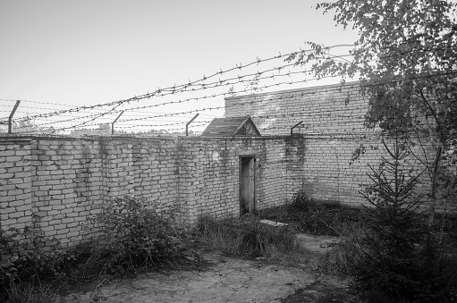 Old abandoned prison with barbed wire. Black and white.