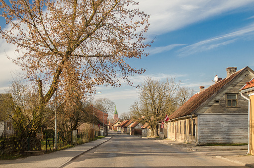 Street with historical houses, lutheran church and latvian flags in sunny autumn day, Kuldiga, Latvia
