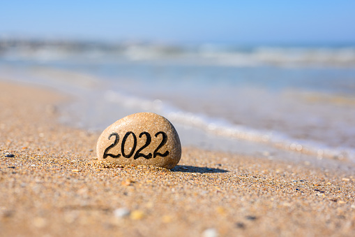 A flat stone with the inscription 2022 stands on the seashore.