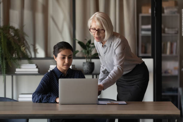 istock Confident mature businesswoman mentor training Indian intern, using laptop 1337433777