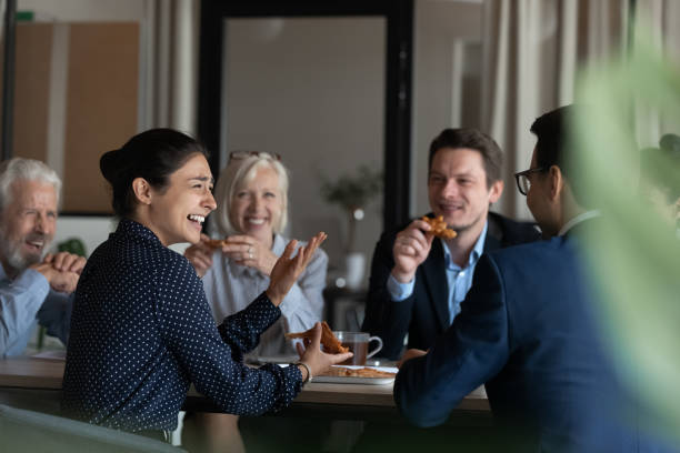 excited diverse employees eating pizza during break in office together - pizza eating african descent lunch imagens e fotografias de stock