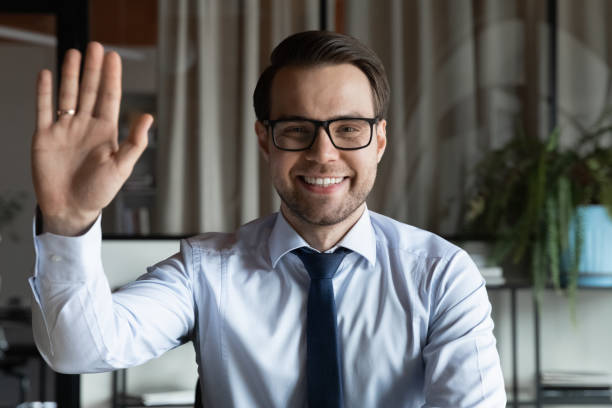head shot portrait of smiling businessman in glasses waving hand - gesprek coaching detail stockfoto's en -beelden