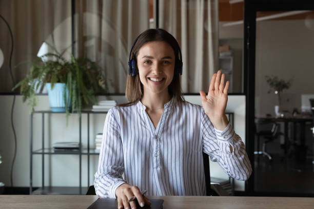 head shot portrait smiling businesswoman in headphones waving hand - gesprek coaching detail stockfoto's en -beelden
