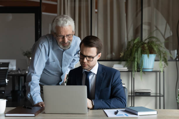 istock Confident mature businessman executive with colleague working on online project 1337433847