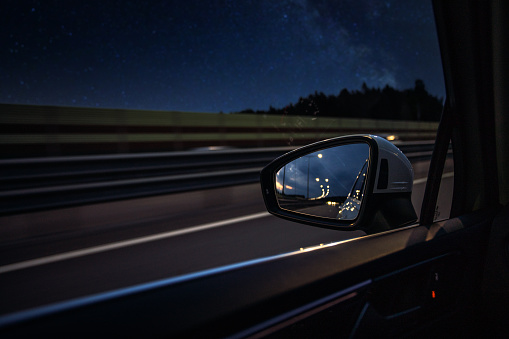 Rear view mirror of a car in the night trip