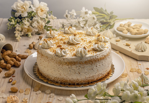 Homemade cake with whipped cream and nuts on wooden background