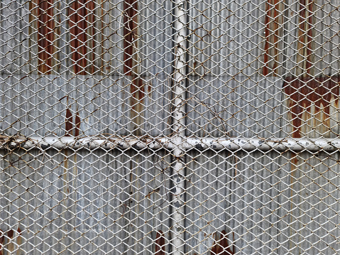 Full Frame Background of Wire Mesh Wall Against Rusty Corrugated Zinc Sheets