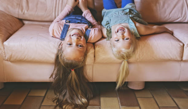 istock Shot of two sisters hanging upside down while lying on their couch 1337438357