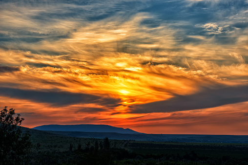 A brightly colored sunset. The sun is behind the clouds and beautifully highlights their texture