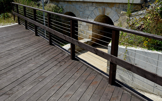 wooden bridge with a stone foundation newly built for cyclists over a stream by the pond. wooden beams connected by screws and rope stainless steel cable railings