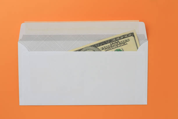 istock Classic white new mail envelope with dollars inside on an orange background. Copy space for text 1337442841