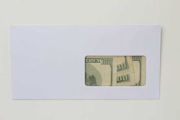 istock Classic white new mail envelope with dollars inside on a white wooden background. Copy space for text 1337443599