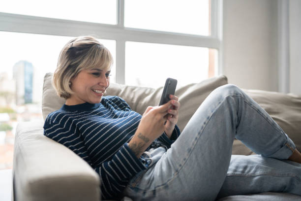 istock Happy young woman using smartphone at home 1337447580