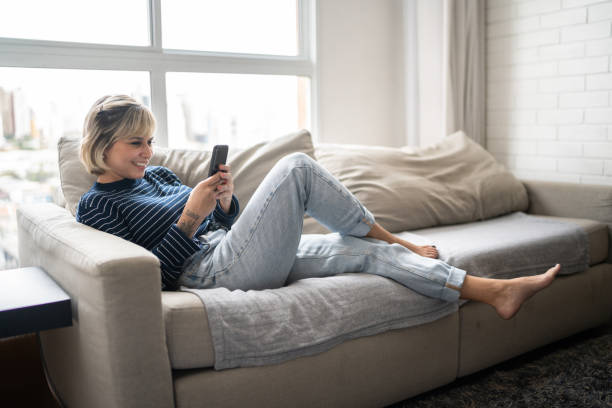 istock Happy young woman using smartphone at home 1337447937