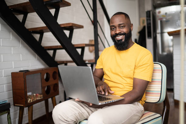 istock Portrait of a happy man using laptop at home 1337447954
