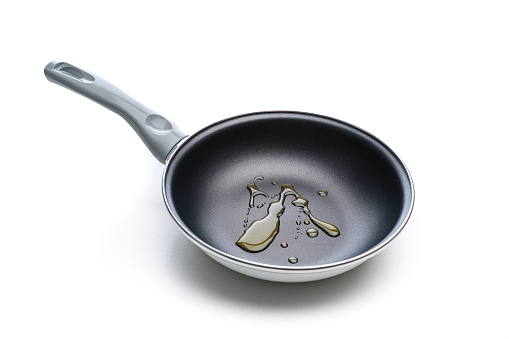 Front view of a new skillet with cooking oil spills isolated on white background.