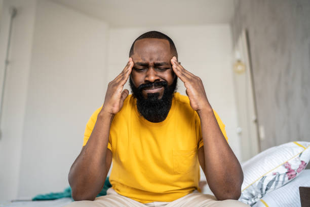 man waking up with headache at home - ressaca imagens e fotografias de stock