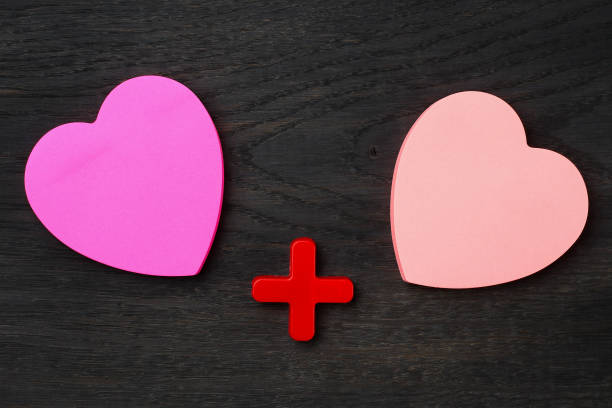 istock Two blank heart shaped stickers with plus sign. Creative symbolic background 1337449438