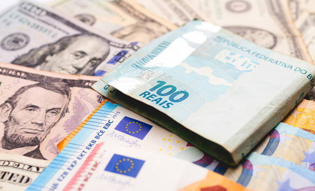 real (brl) e dollaro usa. una banconota brasiliana da 100 reais su banconote da un dollaro. concetti di scambio, investimenti internazionali e l'economia brasiliana. - currency exchange currency european union currency dollar foto e immagini stock