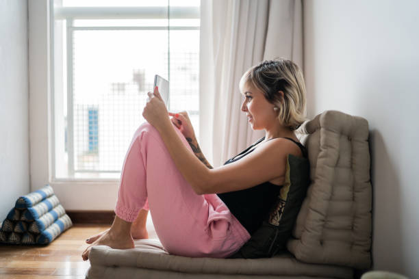 istock Woman sitting on a futon using digital tablet at home 1337449726