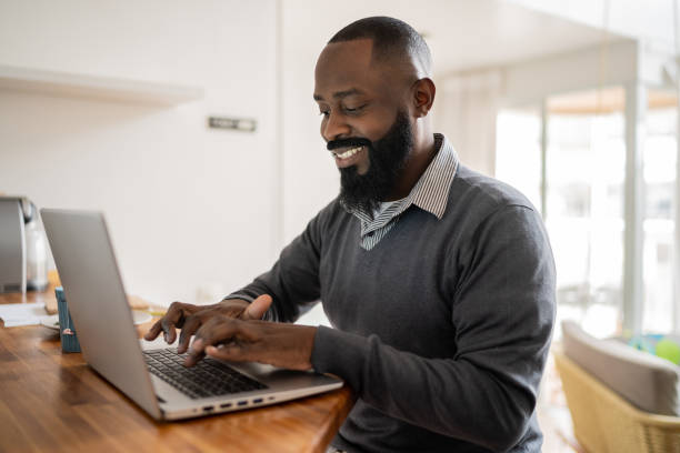 istock Mid adult man using laptop working at home 1337451760