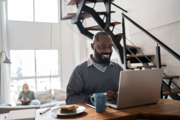 istock Mid adult man using laptop working at home 1337451780
