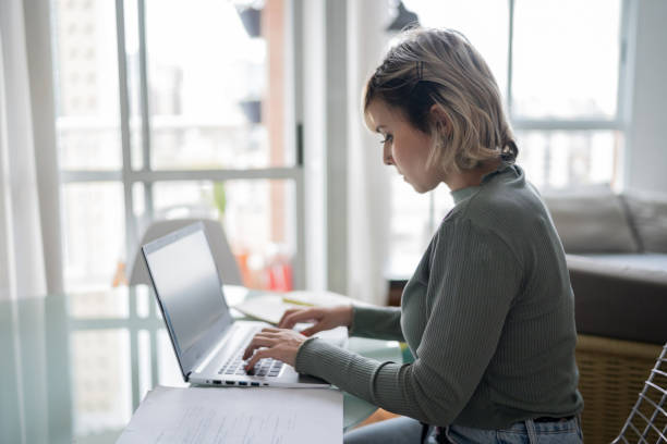 istock Mid adult woman using laptop working at home 1337451898