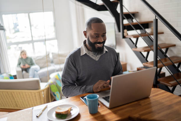 istock Mid adult man using laptop working at home 1337451904