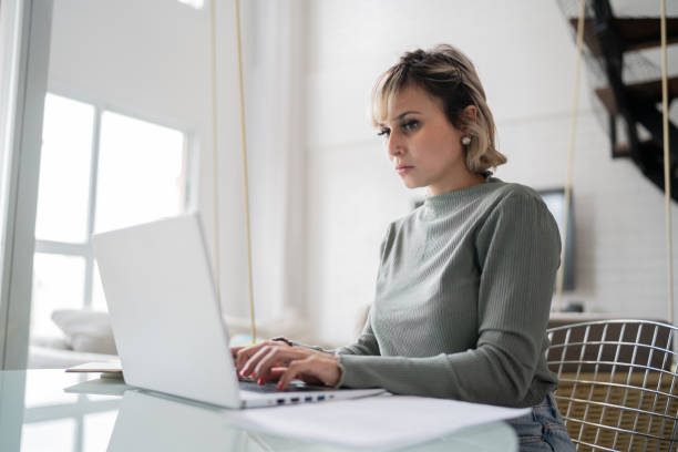 istock Mid adult woman using laptop working at home 1337451960
