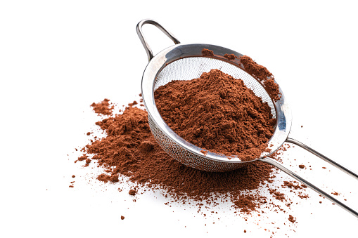 Close up view of a metal sieve filled with cocoa powder isolated on white background