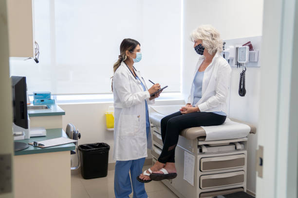 mulher idosa mascarada em um consultório médico - examination table - fotografias e filmes do acervo