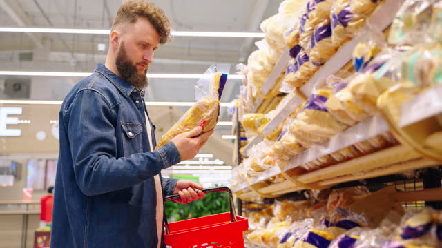 adult man is choosing bread in supermarket, taking packed loaf gluten free