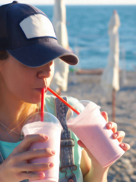 istock A girl in a cap drinks milkshakes through tubes from two glasses at the same time on the beach on a summer day 1337455933