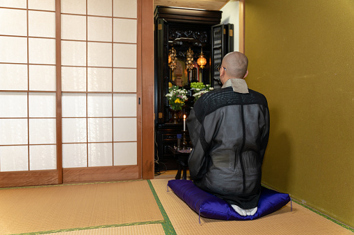 A photo of a Japanese monk praying at a Buddhist altar