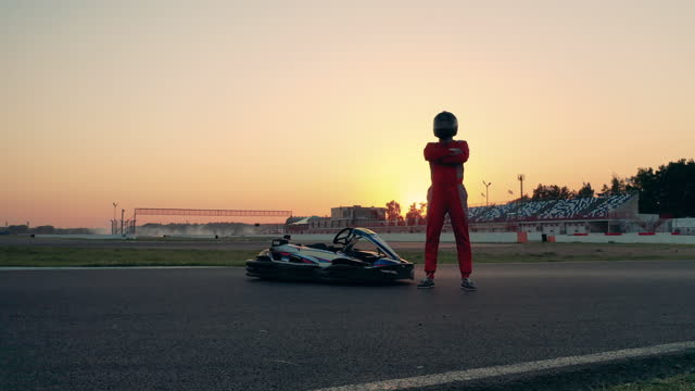 A racer is standing next to a car and puts a helmet on
