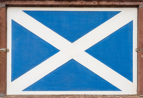 Close-up of a Saltire, the Scottish flag, painted on a stone wall surface.
