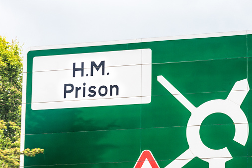 A UK road sign with directions to a prison.