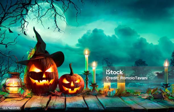 Halloween At Night Pumpkins With Witch Hat And Candles On Table In Mystery Landscape Stock Photo - Download Image Now