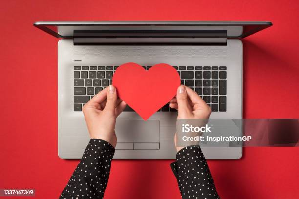 Above Photo Of Grey Laptop And Hands Holding A Red Paper Heart Isolated On The Red Backdrop Stock Photo - Download Image Now