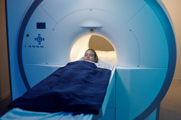 istock Little girl lying on long medical table while moving into mri scan machine 1337470173