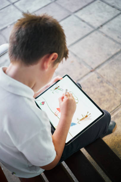 one little spanish school boy drawing on a tablet sitting on bench in park - school bench above bildbanksfoton och bilder