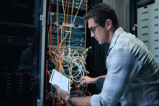 istock Cropped shot of a handsome young male programmer working on a tablet in a server room 1337471389