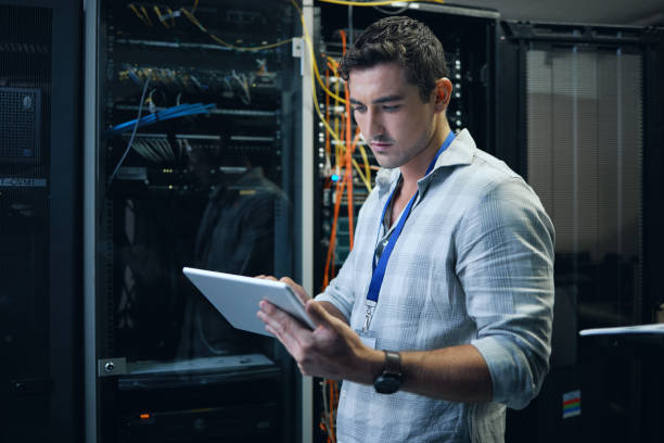 istock Cropped shot of a handsome young male programmer working on a tablet in a server room 1337471392