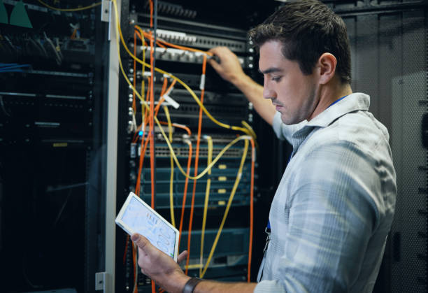 istock Cropped shot of a handsome young male programmer working on a tablet in a server room 1337471394