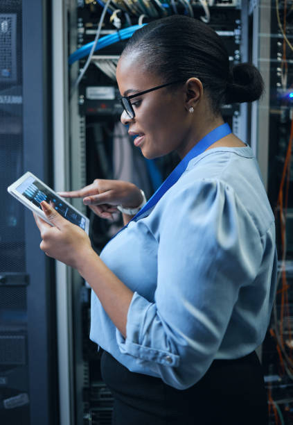 istock Cropped shot of an attractive female programmer working on a tablet in a server room 1337471413