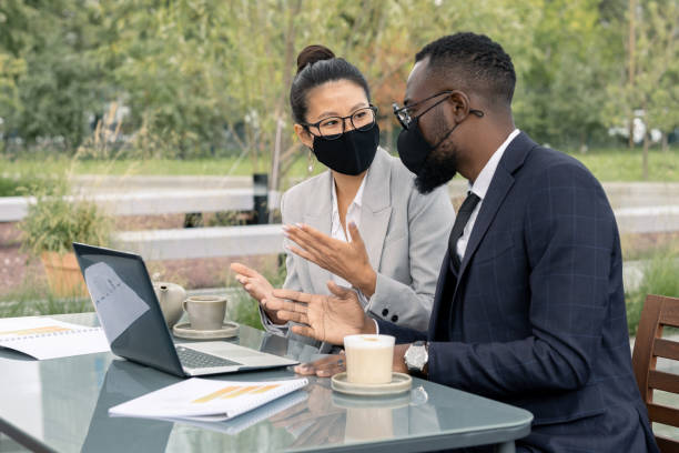 istock Two confident white collar workers in masks discussing new business project 1337472685