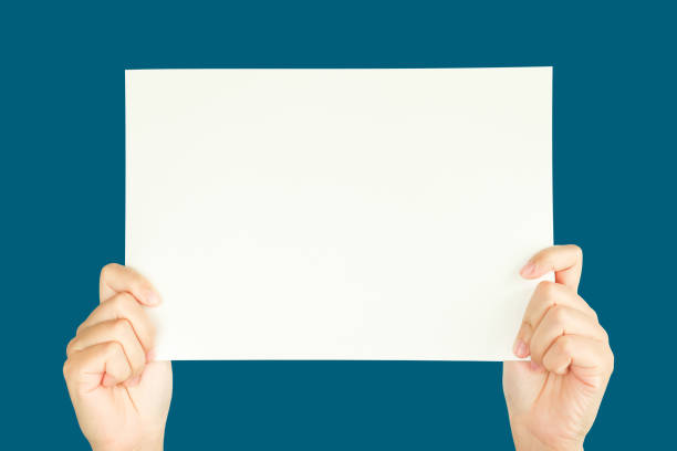 istock women hand holding white blank paper isolated on blue background with clipping path 1337474206