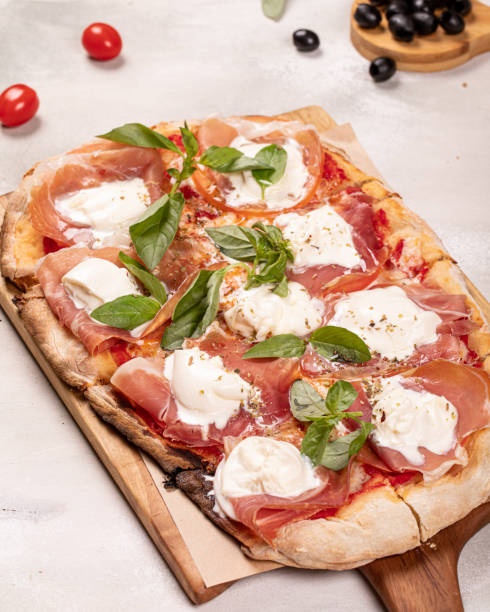 istock Italian roman rectangular pizza with prosciutto and mozzarella on wooden board on white rustic background 1337477605